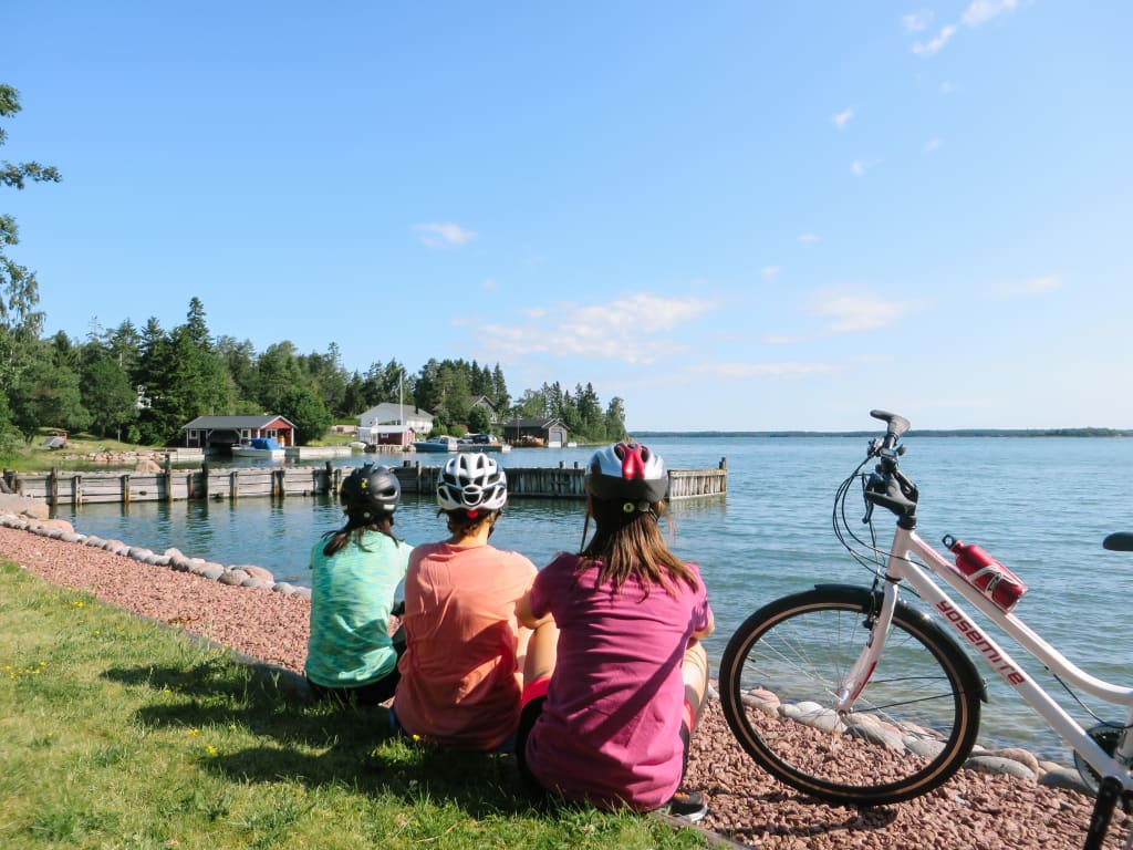 Cicloturisti seduti sulla riva si godono il panorama in riva al mare, relax all'aria aperta, vacanze in bici